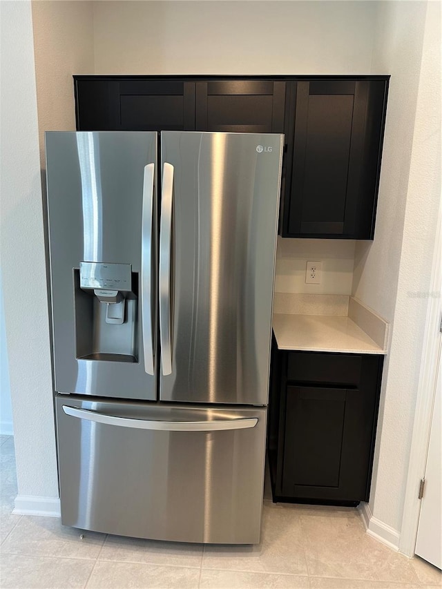 kitchen with stainless steel fridge, light countertops, baseboards, and dark cabinetry