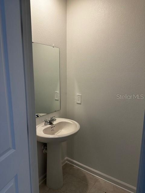 bathroom with tile patterned floors, baseboards, and a sink