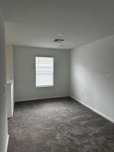 carpeted spare room featuring baseboards and a textured ceiling