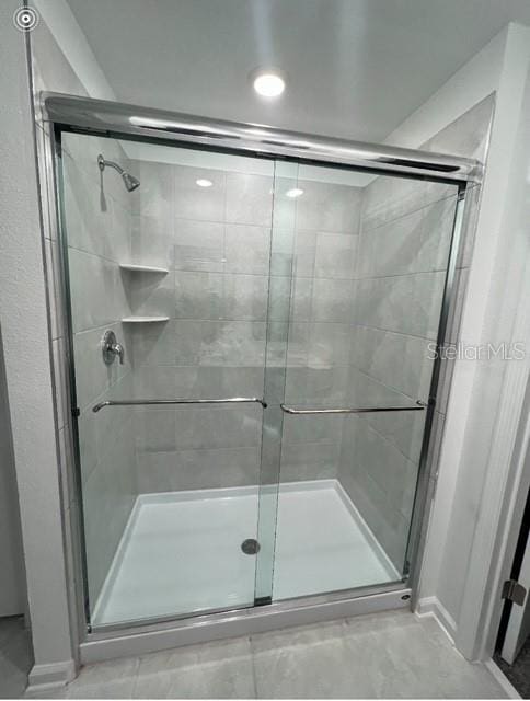 full bath featuring a shower stall and baseboards