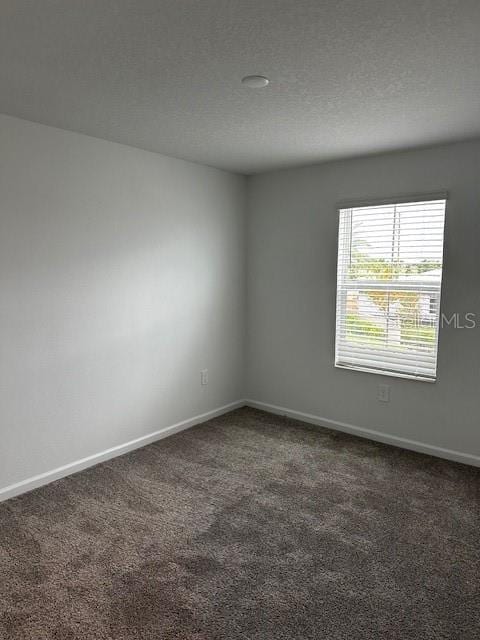 carpeted spare room with baseboards and a textured ceiling