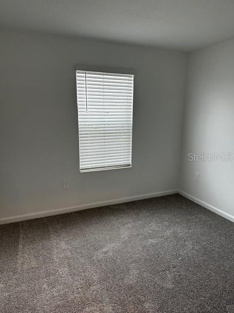spare room featuring carpet and baseboards