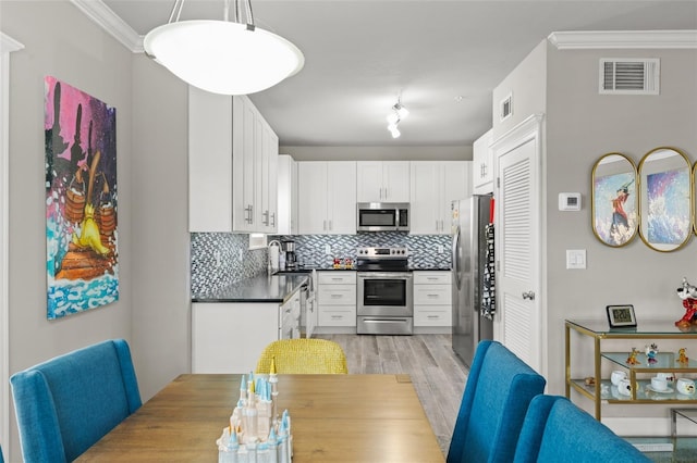 438 Water St Unit 438, Celebration, FL 34747 - kitchen with stainless steel appliances, dark countertops, crown molding, tasteful backsplash, and light wood-style floors