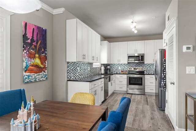 438 Water St Unit 438, Celebration, FL 34747 - kitchen with appliances with stainless steel finishes, light wood-style flooring, tasteful backsplash, dark countertops, and white cabinetry