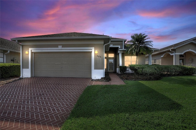 124 Ashton Dr, Davenport, FL 33837 - ranch-style home with stucco siding, decorative driveway, a garage, and a lawn