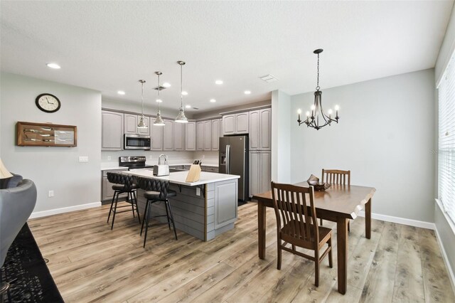 1272 Bonita Canyon Dr, Kissimmee, FL 34759 - kitchen featuring appliances with stainless steel finishes, gray cabinets, light wood-style floors, a center island with sink, and a chandelier