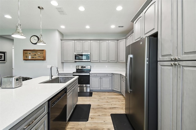 1272 Bonita Canyon Dr, Kissimmee, FL 34759 - kitchen with appliances with stainless steel finishes, gray cabinetry, a sink, light wood-type flooring, and decorative light fixtures