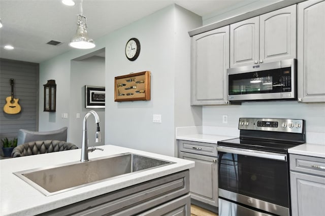1272 Bonita Canyon Dr, Kissimmee, FL 34759 - kitchen featuring stainless steel appliances, a sink, light countertops, gray cabinetry, and decorative light fixtures