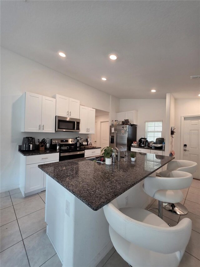 2034 Old Pasture Ln, Lakeland, FL 33801 - kitchen featuring stainless steel appliances, a breakfast bar, white cabinetry, dark stone counters, and recessed lighting