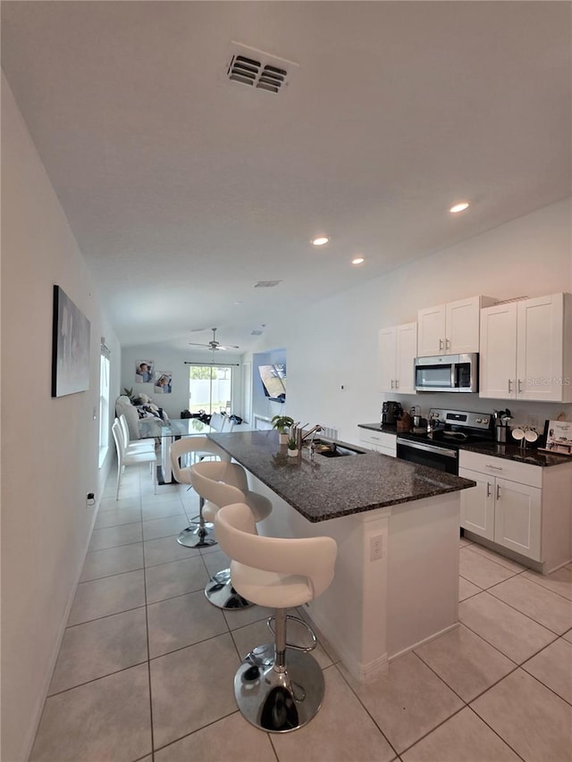 2034 Old Pasture Ln, Lakeland, FL 33801 - kitchen featuring appliances with stainless steel finishes, white cabinetry, light tile patterned floors, a breakfast bar area, and recessed lighting