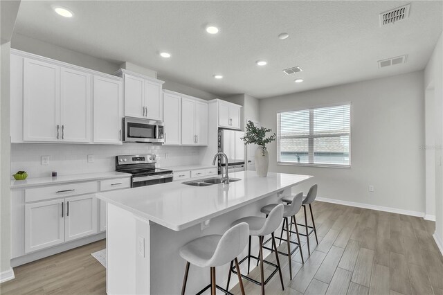 12190 Plumpton Dr, Winter Garden, FL 34787 - kitchen with appliances with stainless steel finishes, a sink, an island with sink, baseboards, and a breakfast bar