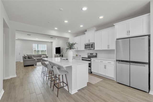 12190 Plumpton Dr, Winter Garden, FL 34787 - kitchen featuring stainless steel appliances, light wood finished floors, white cabinetry, a breakfast bar area, and recessed lighting