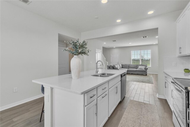 12190 Plumpton Dr, Winter Garden, FL 34787 - kitchen featuring a sink, appliances with stainless steel finishes, wood finished floors, white cabinetry, and light countertops