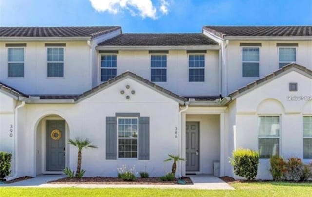 townhome / multi-family property with stucco siding and a front yard
