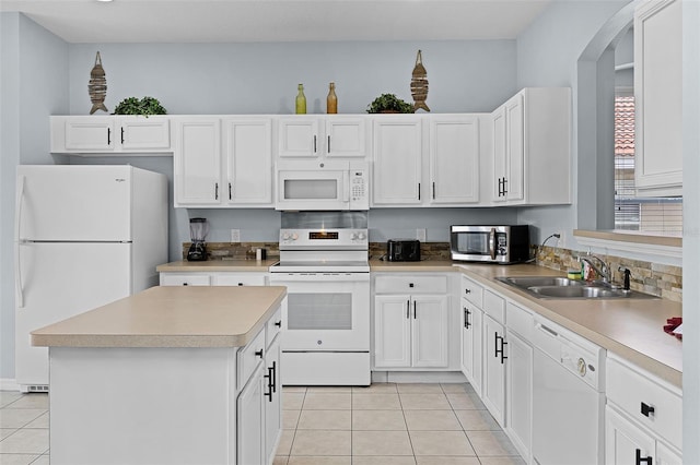 321 Rosso Dr, Davenport, FL 33837 - kitchen featuring white appliances, a sink, light tile patterned floors, a kitchen island, and arched walkways