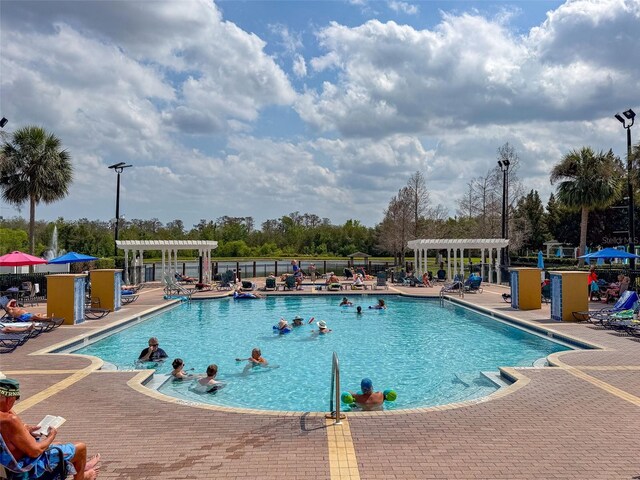 2620 Lodi Cir Unit 103, Kissimmee, FL 34746 - community pool featuring a pergola, a patio area, and view of wooded area