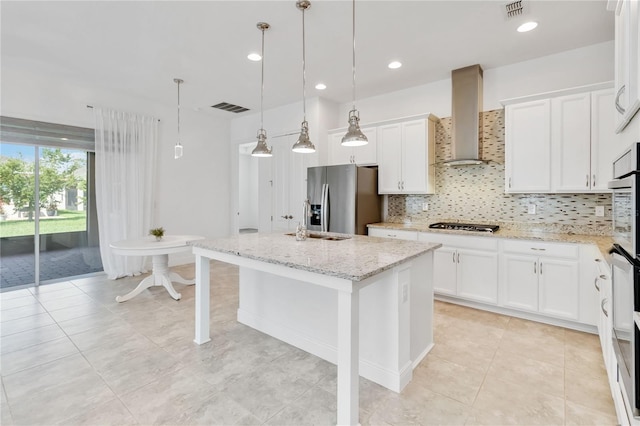 5009 E Fountainwood Dr, Saint Cloud, FL 34772 - kitchen with wall chimney exhaust hood, stainless steel appliances, tasteful backsplash, white cabinets, and a center island with sink