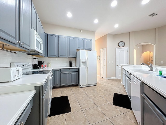 518 Brighton Dr, Davenport, FL 33897 - kitchen with white appliances, gray cabinetry, a sink, arched walkways, and light tile patterned flooring