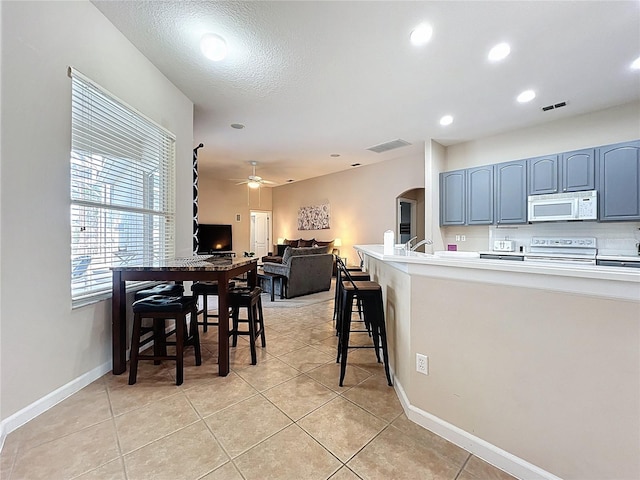 518 Brighton Dr, Davenport, FL 33897 - kitchen featuring white microwave, range with electric cooktop, arched walkways, ceiling fan, and light tile patterned flooring