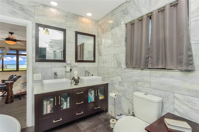 955 Mansfield Rd, Tavares, FL 32778 - full bathroom with tile walls, toilet, tile patterned flooring, a ceiling fan, and double vanity