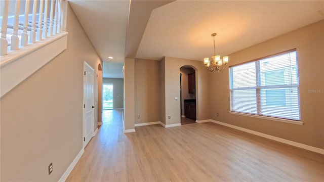 6957 Northwich Dr, Windermere, FL 34786 - unfurnished dining area featuring arched walkways, light wood finished floors, baseboards, and a chandelier