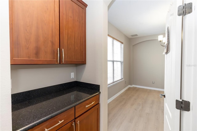 6957 Northwich Dr, Windermere, FL 34786 - kitchen featuring light wood finished floors, dark stone countertops, brown cabinets, and baseboards