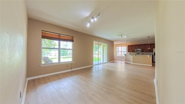 6957 Northwich Dr, Windermere, FL 34786 - unfurnished living room with light wood-style floors, baseboards, and track lighting