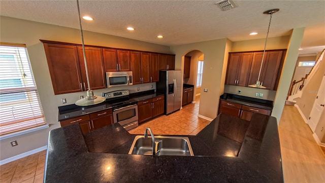 6957 Northwich Dr, Windermere, FL 34786 - kitchen with stainless steel appliances, arched walkways, baseboards, healthy amount of natural light, and a textured ceiling