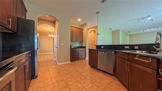 6957 Northwich Dr, Windermere, FL 34786 - kitchen with stainless steel dishwasher, dark countertops, a sink, arched walkways, and light tile patterned floors
