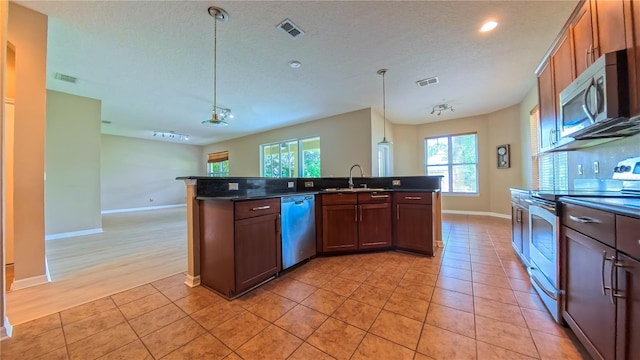 6957 Northwich Dr, Windermere, FL 34786 - kitchen featuring stainless steel appliances, dark countertops, baseboards, a sink, and recessed lighting