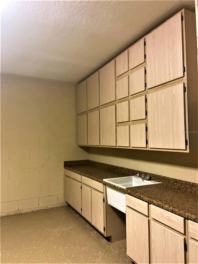 6957 Northwich Dr, Windermere, FL 34786 - kitchen with dark countertops, concrete block wall, a textured ceiling, and a sink