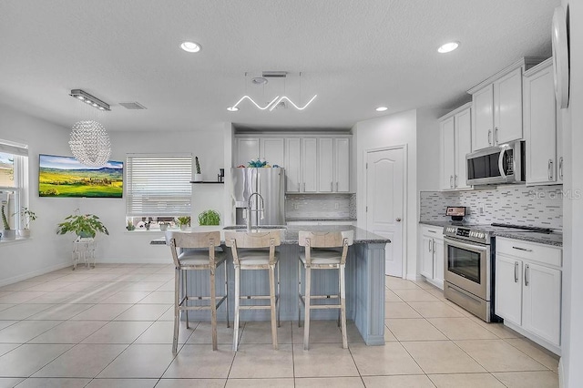 3400 Mt Vernon Way, Kissimmee, FL 34741 - kitchen featuring appliances with stainless steel finishes, tasteful backsplash, light tile patterned flooring, a kitchen breakfast bar, and a textured ceiling