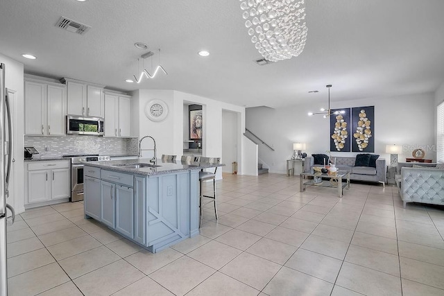 3400 Mt Vernon Way, Kissimmee, FL 34741 - kitchen with stainless steel appliances, a sink, open floor plan, decorative backsplash, and light tile patterned floors