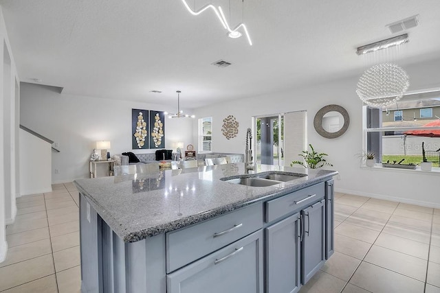 3400 Mt Vernon Way, Kissimmee, FL 34741 - kitchen with a sink, a chandelier, light tile patterned floors, light stone countertops, and a center island with sink