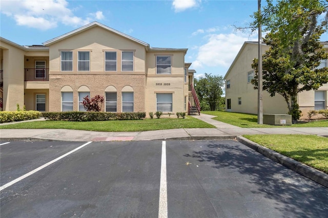 2828 Club Cortile Cir Unit B, Kissimmee, FL 34746 - view of front of property featuring uncovered parking, a front lawn, stairway, and stucco siding