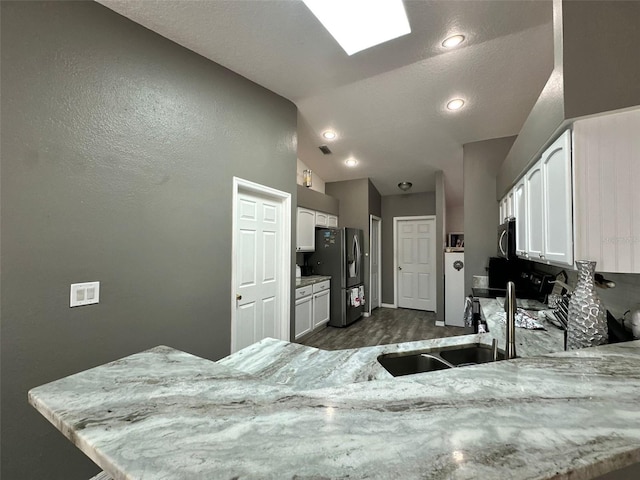 2410 Sweetwater Blvd, Saint Cloud, FL 34772 - kitchen with white cabinets, vaulted ceiling, stainless steel refrigerator with ice dispenser, light stone countertops, and baseboards