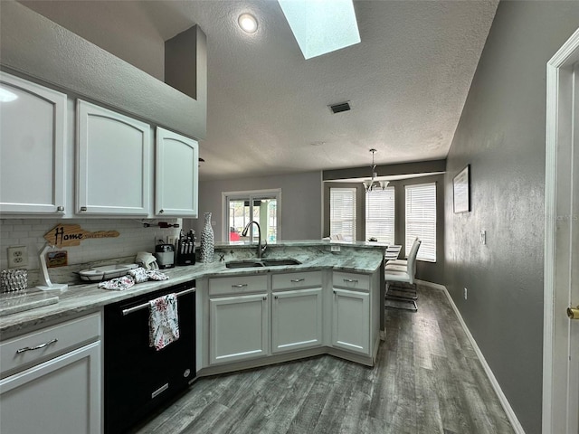 2410 Sweetwater Blvd, Saint Cloud, FL 34772 - kitchen with a sink, black dishwasher, wood finished floors, a peninsula, and white cabinetry