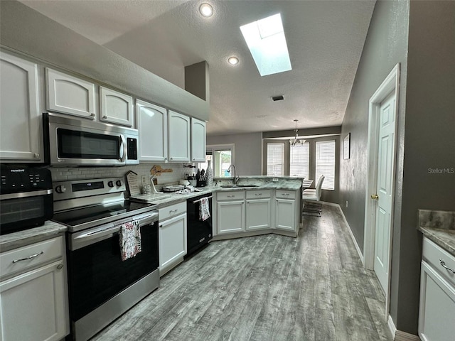 2410 Sweetwater Blvd, Saint Cloud, FL 34772 - kitchen with stainless steel appliances, a skylight, a peninsula, a sink, and a textured ceiling