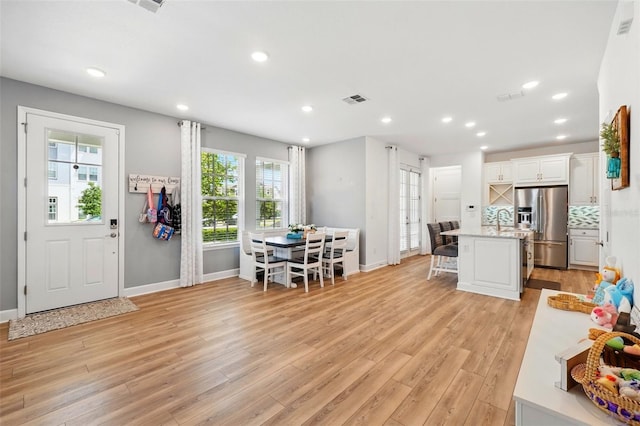 7400 Estuary Lake Loop, Celebration, FL 34747 - kitchen with stainless steel fridge, a kitchen bar, light wood-style flooring, white cabinets, and recessed lighting