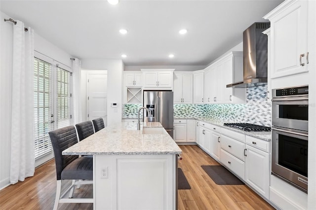 7400 Estuary Lake Loop, Celebration, FL 34747 - kitchen with appliances with stainless steel finishes, wall chimney exhaust hood, a breakfast bar area, white cabinetry, and recessed lighting