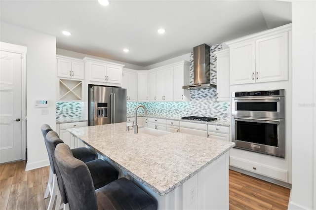 7400 Estuary Lake Loop, Celebration, FL 34747 - kitchen featuring stainless steel appliances, wall chimney range hood, a kitchen bar, light wood-style floors, and recessed lighting