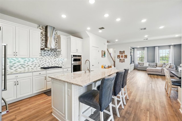 7400 Estuary Lake Loop, Celebration, FL 34747 - kitchen featuring wall chimney range hood, appliances with stainless steel finishes, light wood finished floors, white cabinetry, and recessed lighting