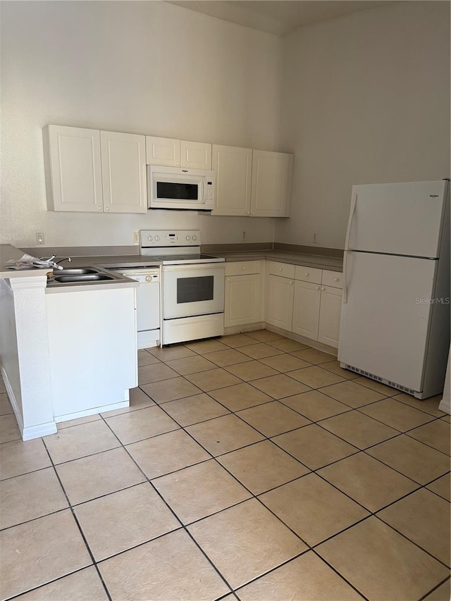 2826 Club Cortile Cir Unit B, Kissimmee, FL 34746 - kitchen featuring white appliances, light tile patterned floors, white cabinetry, a sink, and a towering ceiling