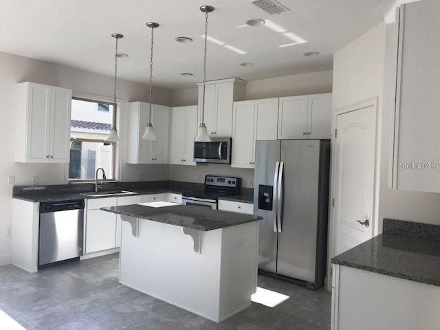 13885 Arclid St, Orlando, FL 32832 - kitchen with appliances with stainless steel finishes, a sink, white cabinets, a kitchen island, and a breakfast bar area