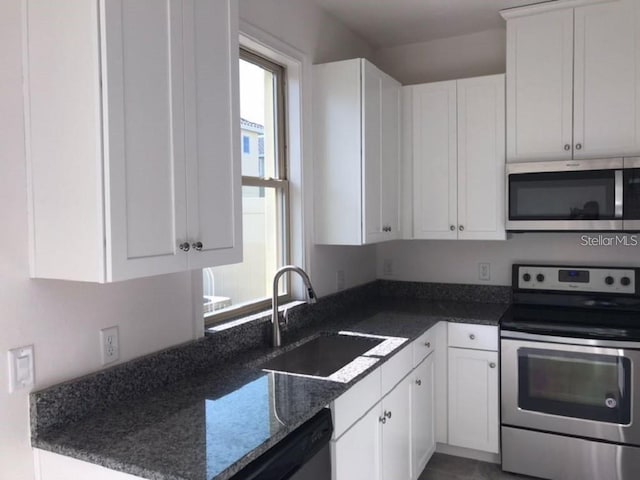 13885 Arclid St, Orlando, FL 32832 - kitchen with stainless steel appliances, a sink, white cabinetry, and dark stone counters