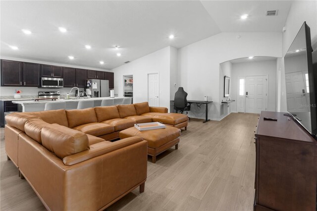 1524 Fleur Dr, Davenport, FL 33837 - living room featuring lofted ceiling, arched walkways, light wood finished floors, and recessed lighting