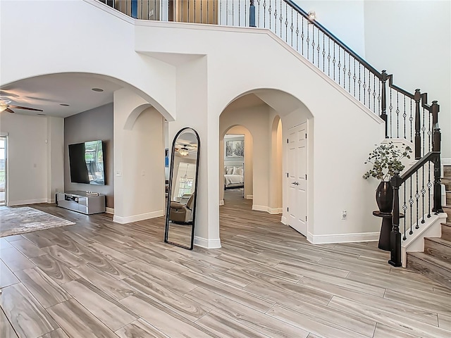 1211 Terralago Way, Kissimmee, FL 34746 - foyer featuring a ceiling fan, a towering ceiling, stairs, light wood-style floors, and baseboards