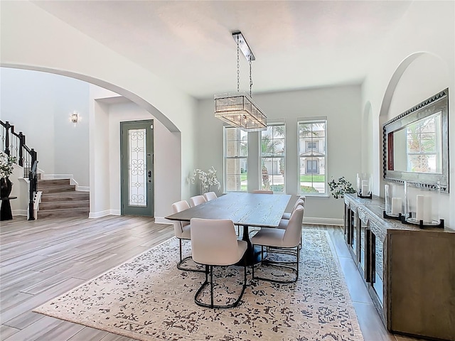 1211 Terralago Way, Kissimmee, FL 34746 - dining room with light wood-style flooring, stairs, arched walkways, and baseboards
