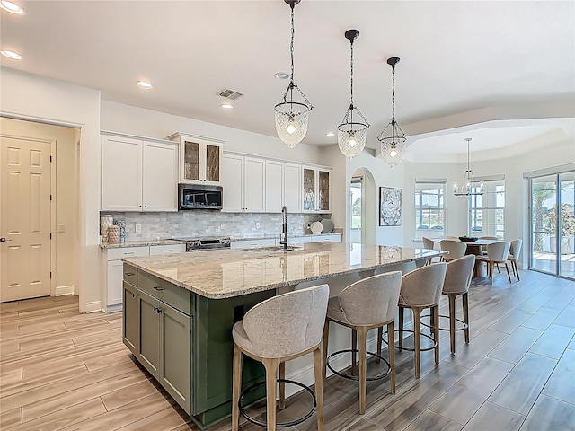 1211 Terralago Way, Kissimmee, FL 34746 - kitchen featuring appliances with stainless steel finishes, recessed lighting, arched walkways, tasteful backsplash, and a large island with sink