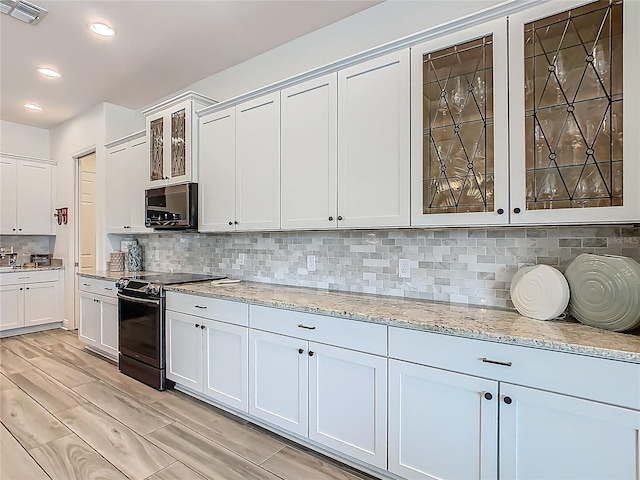 1211 Terralago Way, Kissimmee, FL 34746 - kitchen featuring stainless steel electric range oven, glass insert cabinets, light stone countertops, decorative backsplash, and recessed lighting